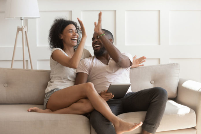 Excited african American couple give high five celebrating success